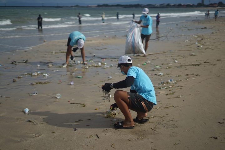 a group of people on a beach doing a beach clean up