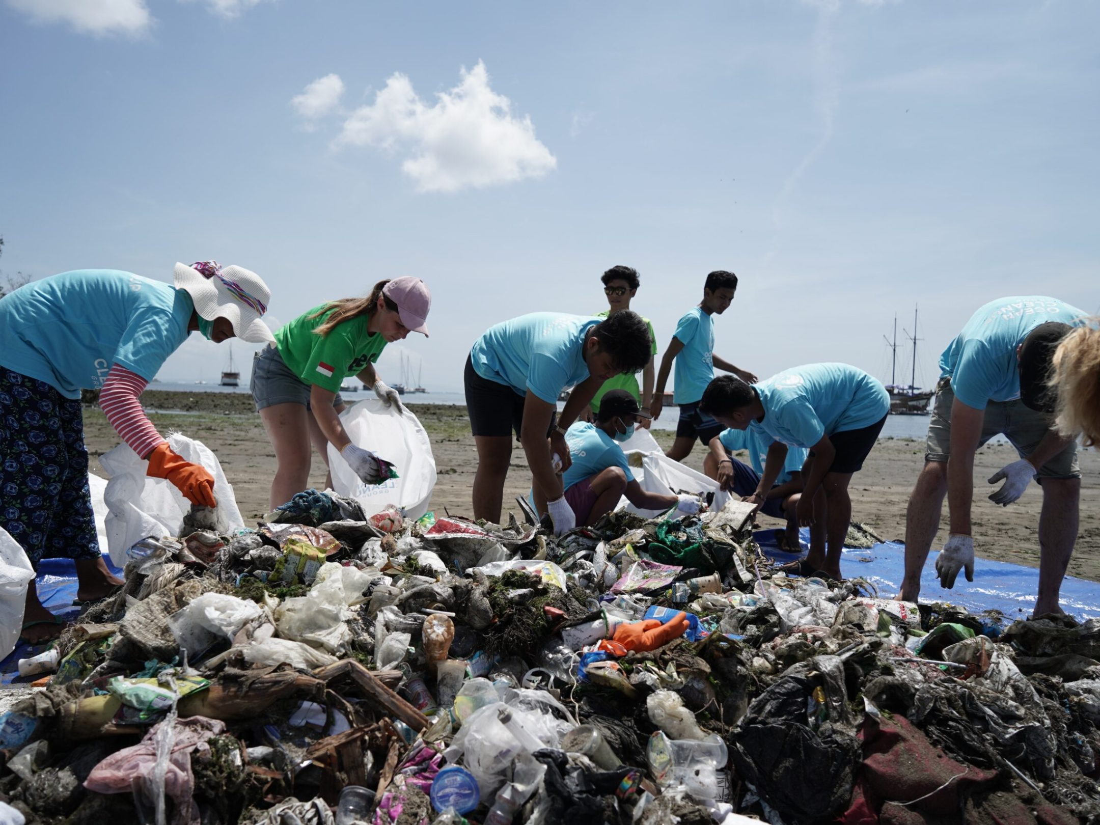 a group of people cleaning up trash on the beach