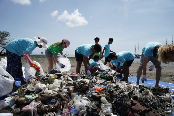 a group of people cleaning up trash on the beach