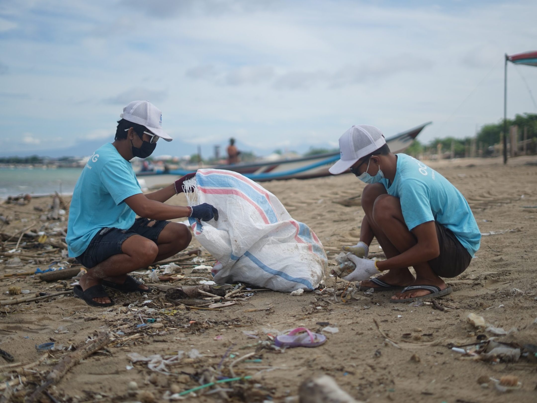 a man sitting on top of a sandy beach doing a beach clean up