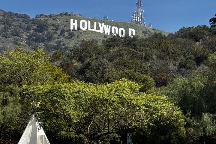 A picnic setup with a teepee and table under the Hollywood sign on a sunny day.